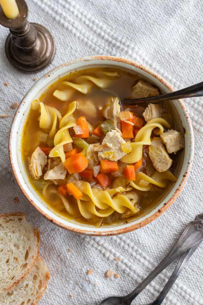 a bowl of chicken noodle soup with a spoon.