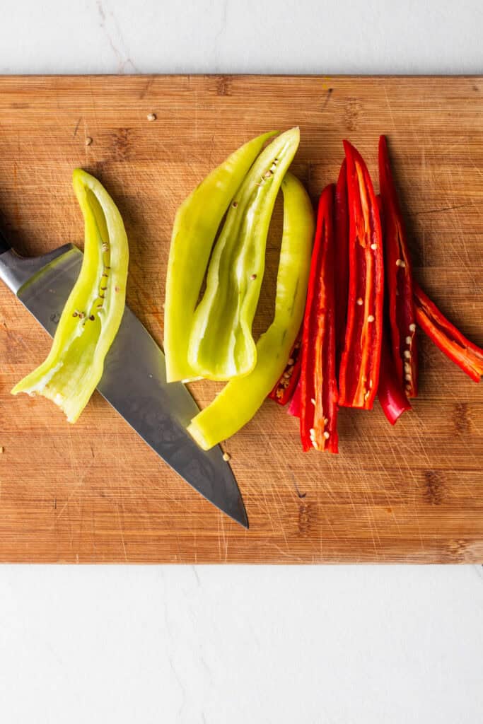 Peppers sliced on a wooden cutting board.