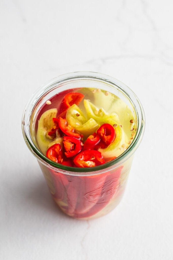 Peppers in a salt water brine in a jar.