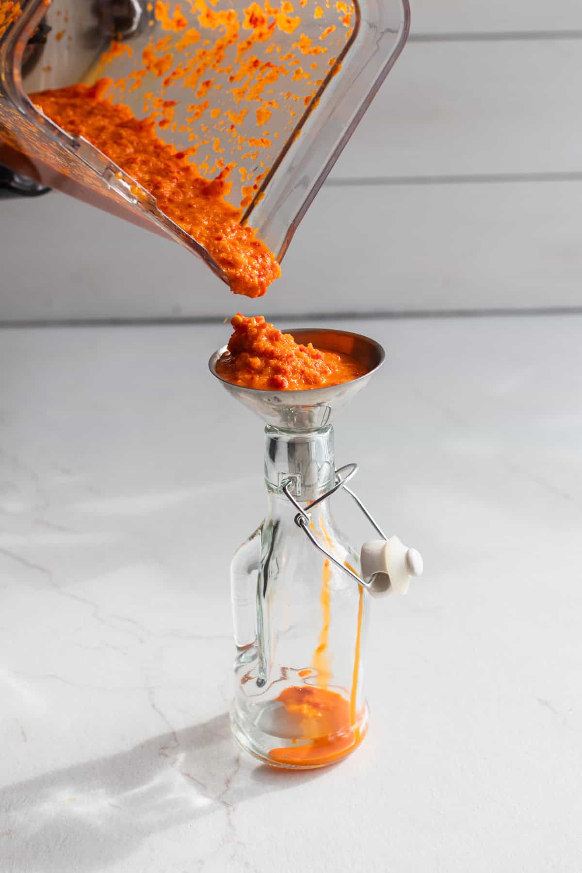 Pouring fermented hot sauce into a jar.