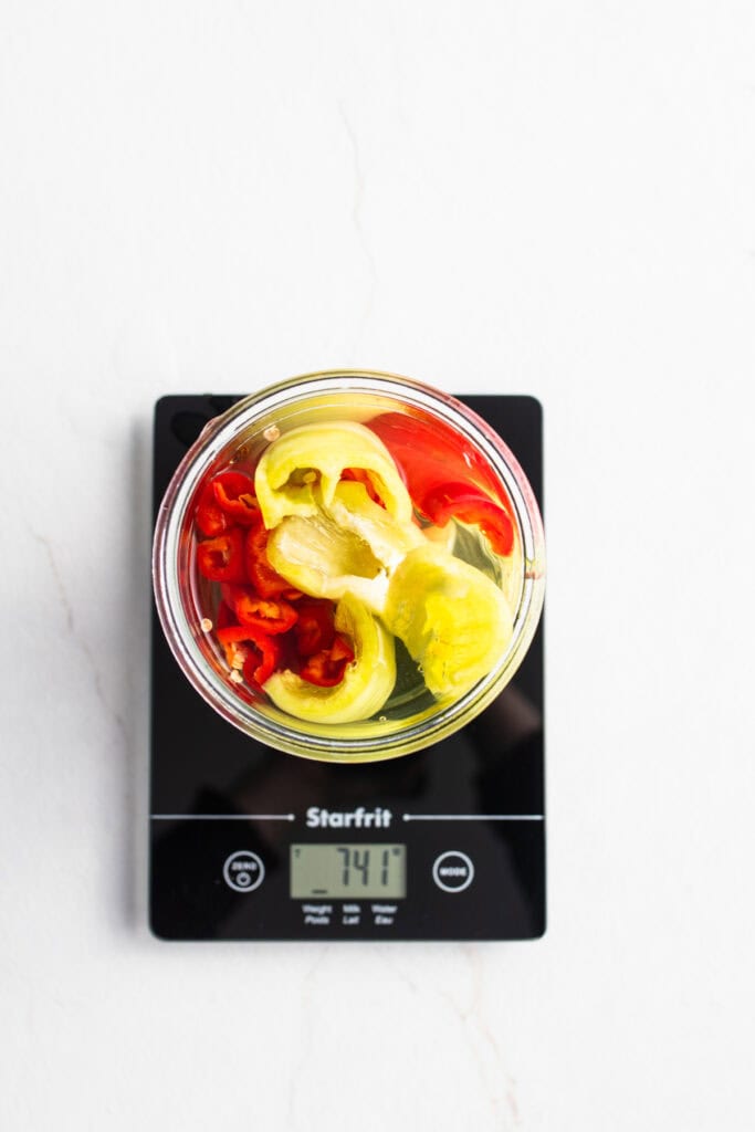 Peppers in a jar on a kitchen scale.