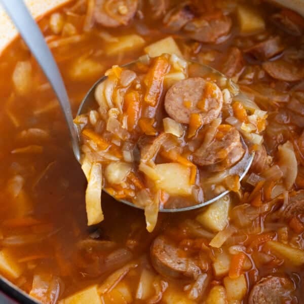 A Dutch oven with soup being ladled out.