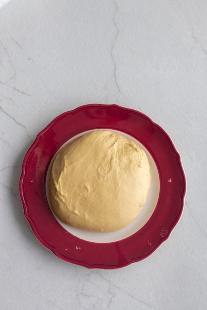 A dough ball resting on a plate. 