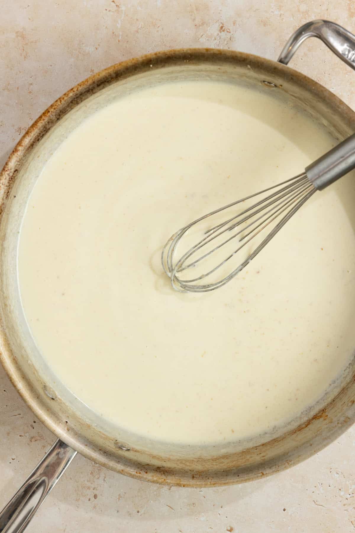 Cream added to a skillet with a whisk.
