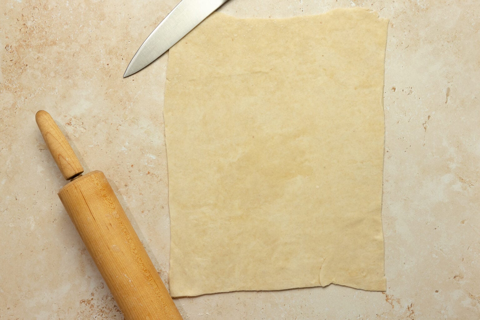 Rolling out pie dough into a thin sheet and cut into a rectangle.