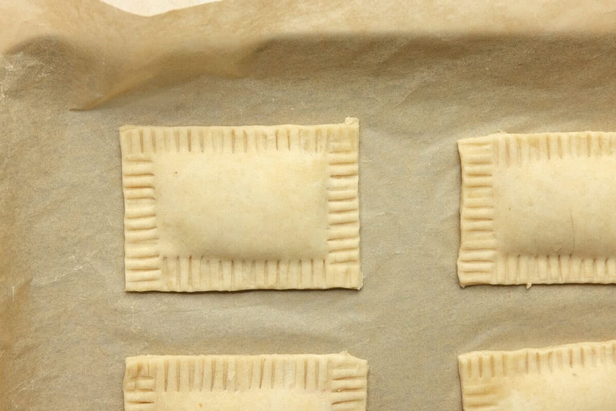 Unbaked homemade pop tarts on a parchment lined baking sheet.