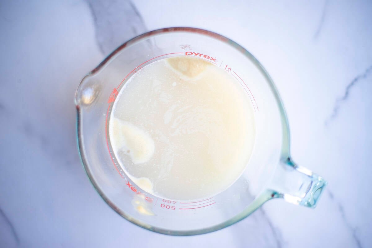 Warm water, honey, and active dry yeast in a glass measuring cup.