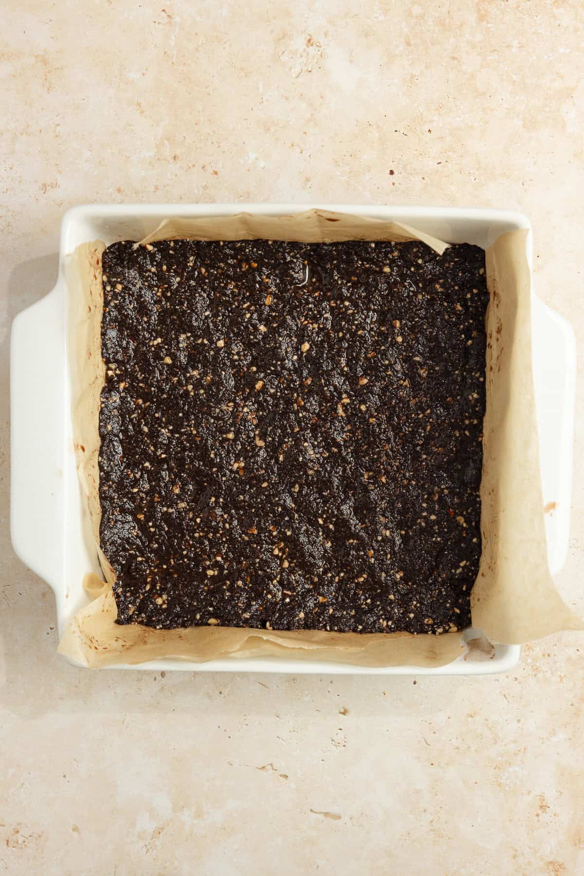 Date and nut mixture pressed in a 9x13 pan lined with parchment paper.
