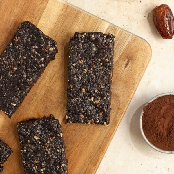 three homemade larabars on a wood cutting board with ingredients surrounding the board.