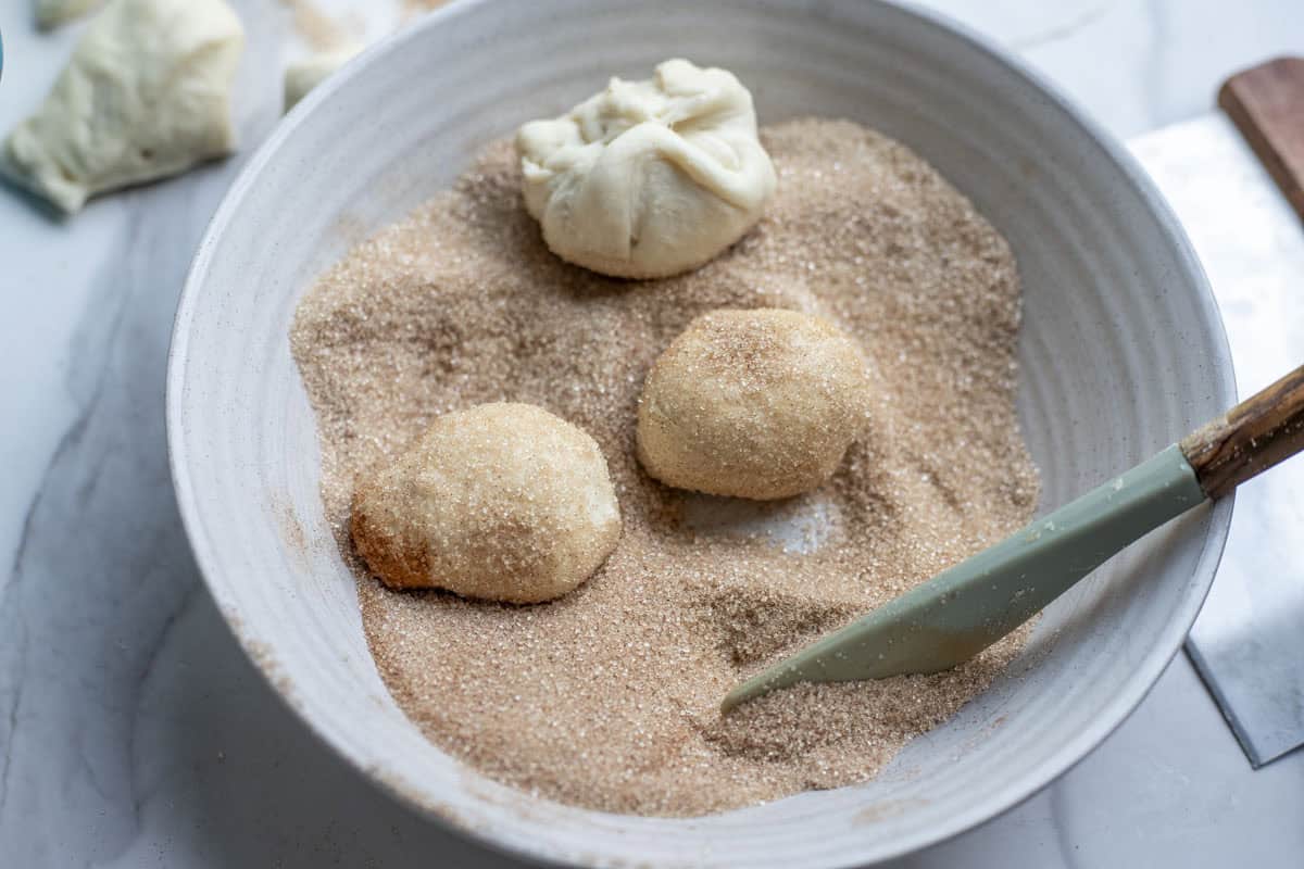rolling dough balls in cinnamon sugar.