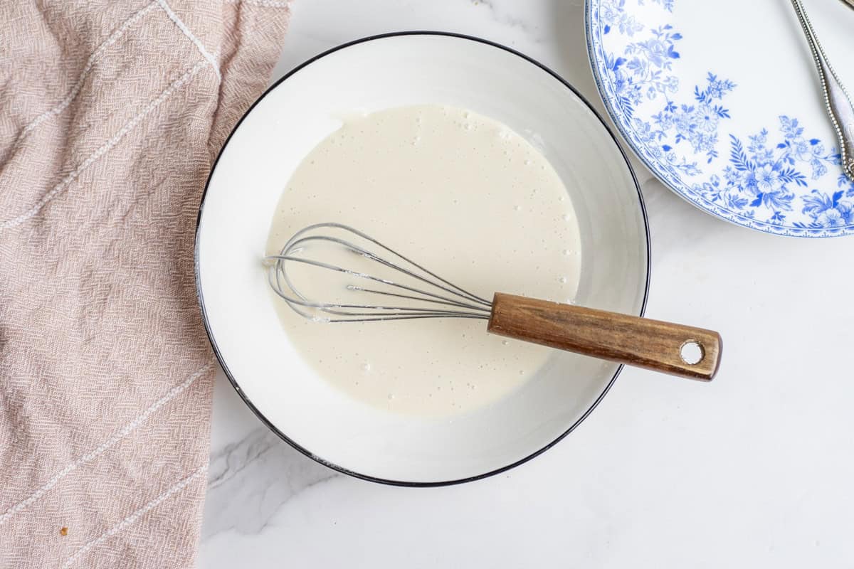 mixing icing in a bowl with a whisk.