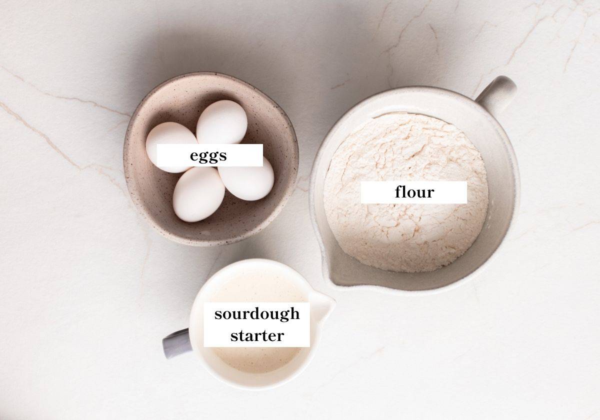 Eggs, flour, and sourdough starter on a countertop. 