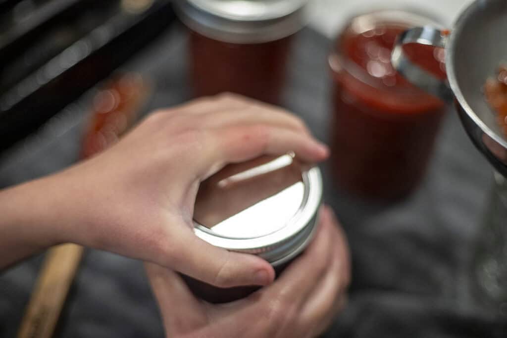 A hand putting a lid on a jar.
