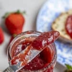 A jar of jam with a knife on top.