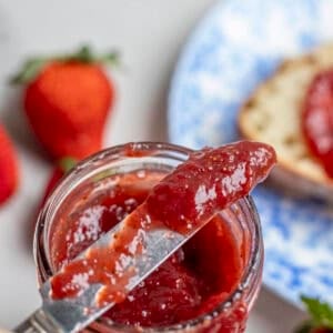 A jar of jam with a knife on top.