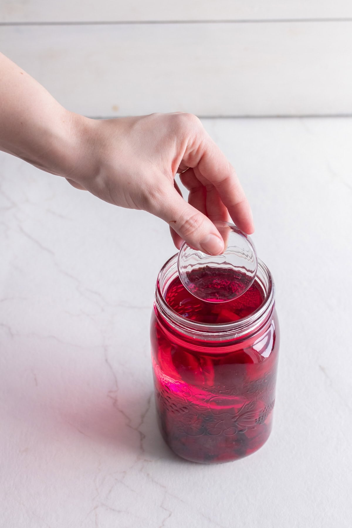 Adding a fermentation weight to a jar of beets and water.