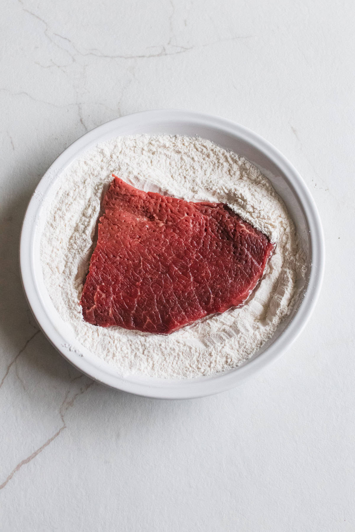 steak being dredged in flour and salt.