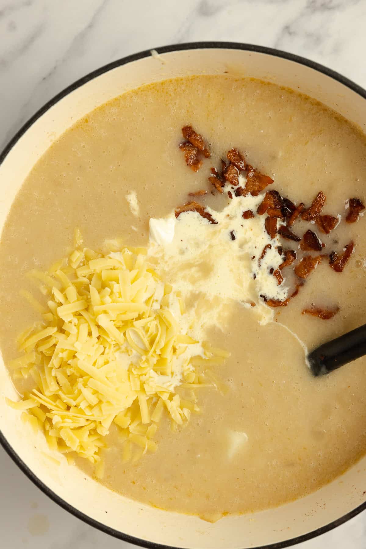 Cheese, sour cream, and cooked bacon added to loaded potato soup.