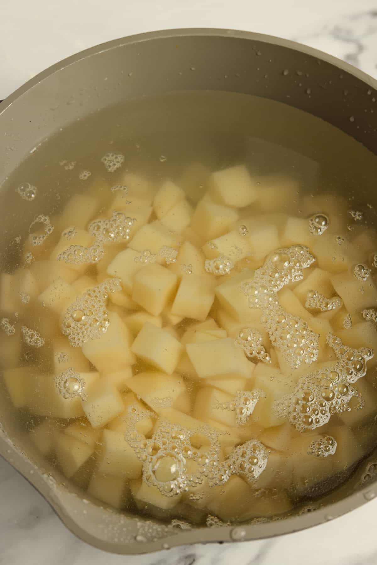 Boiling chopped potatoes in a pot.