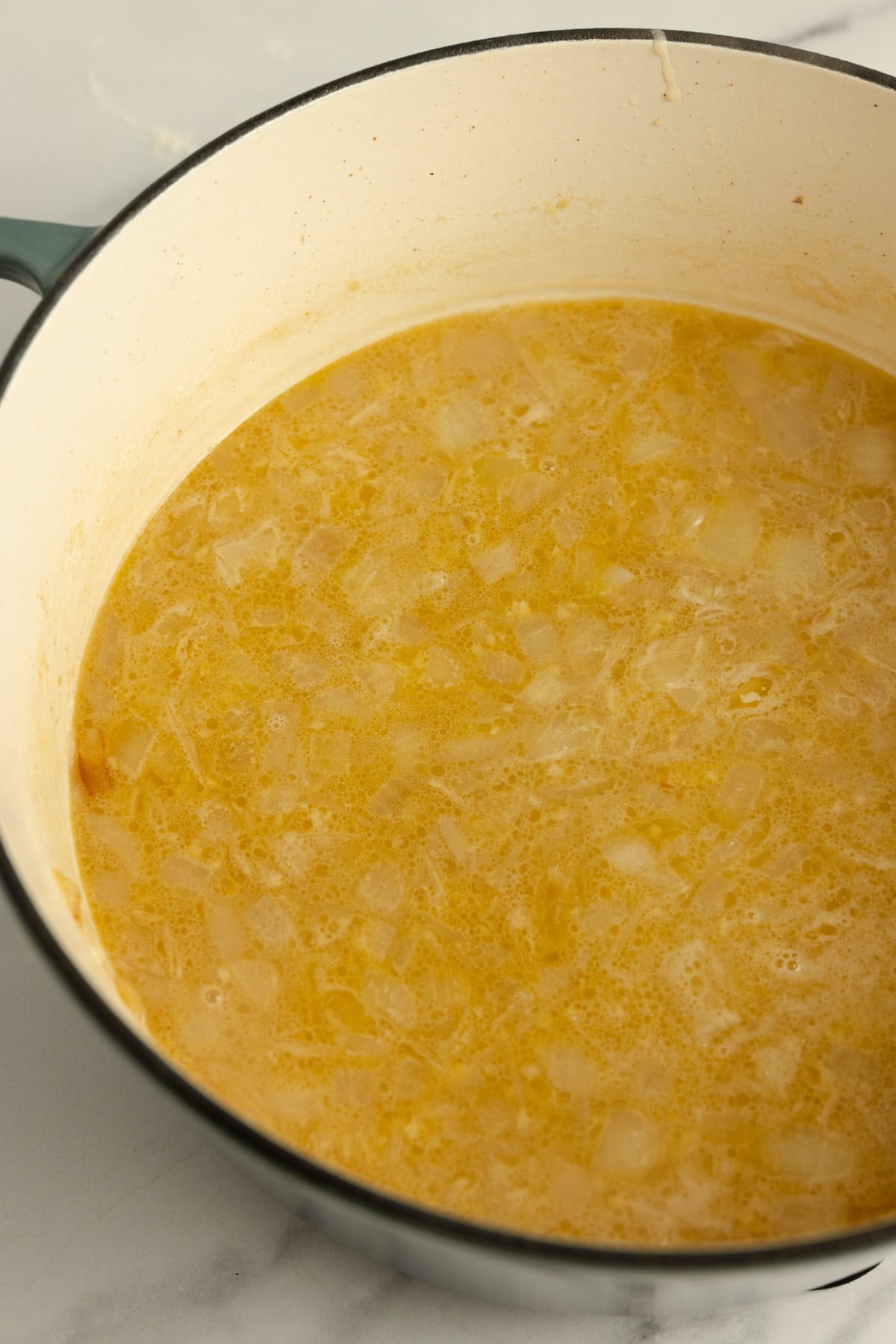 Chicken broth added to pot with onions and flour and brought to a simmer.