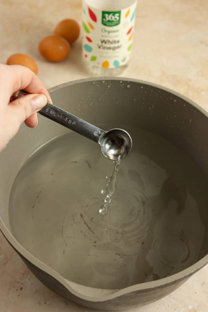 Water in a pot with vinegar being added.