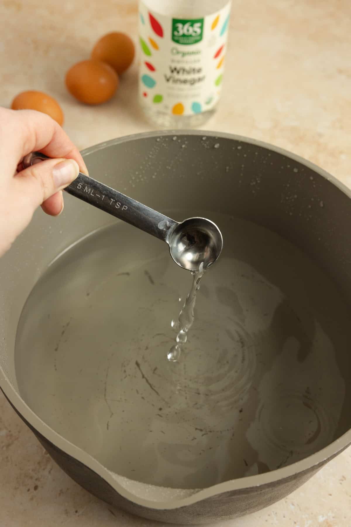 Water in a pot with vinegar being added.