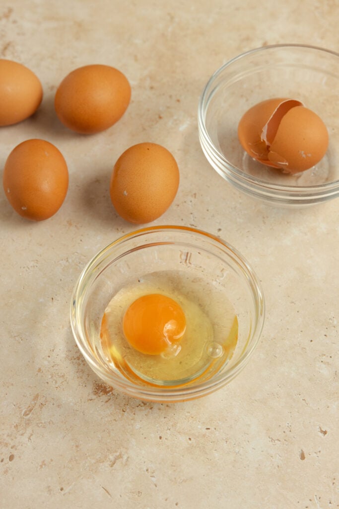 raw egg in a small bowl with whole eggs in the background.