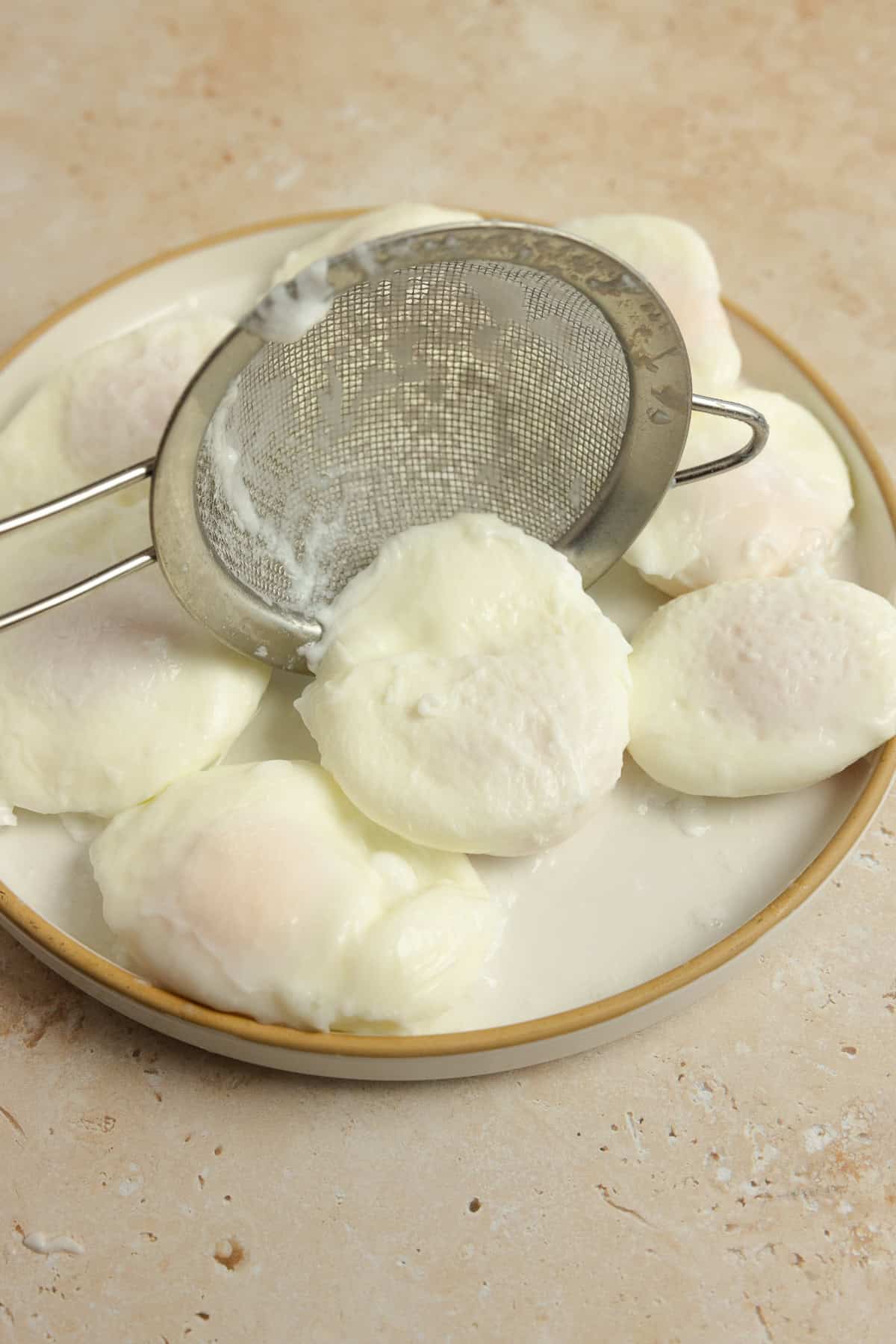 Placing a poached egg on a plate with more poached eggs.