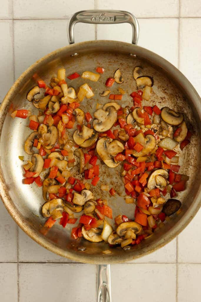 Peppers and mushrooms in a skillet.