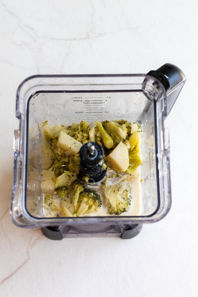 a blender on the counter blending up cooked vegetables and potatoes.