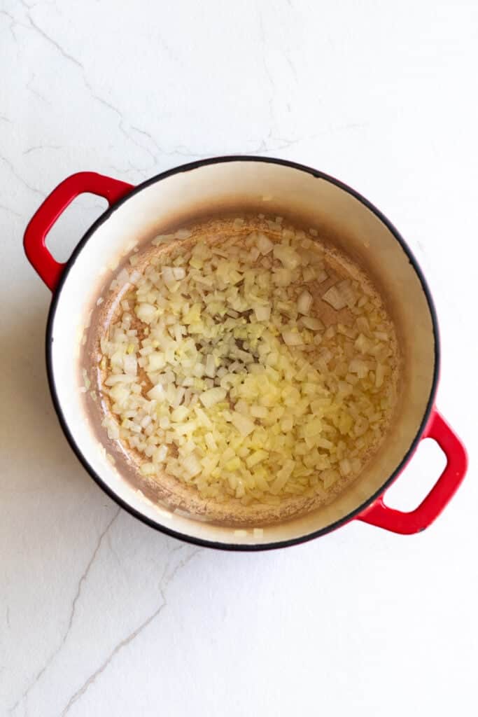 Onions and garlic cooking in a pot with melted butter.