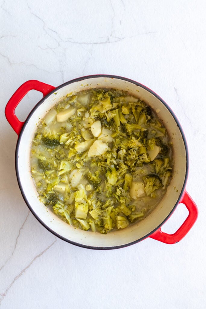broccoli, potatoes, and broth simmering in a dutch oven.