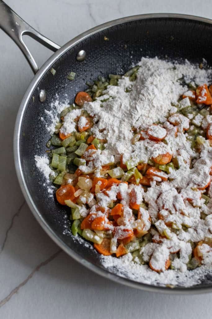 Softened celery, carrots, and onions in a skillet coated with flour.