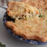 A slice of chicken pot pie being lifted out of a pie plate.