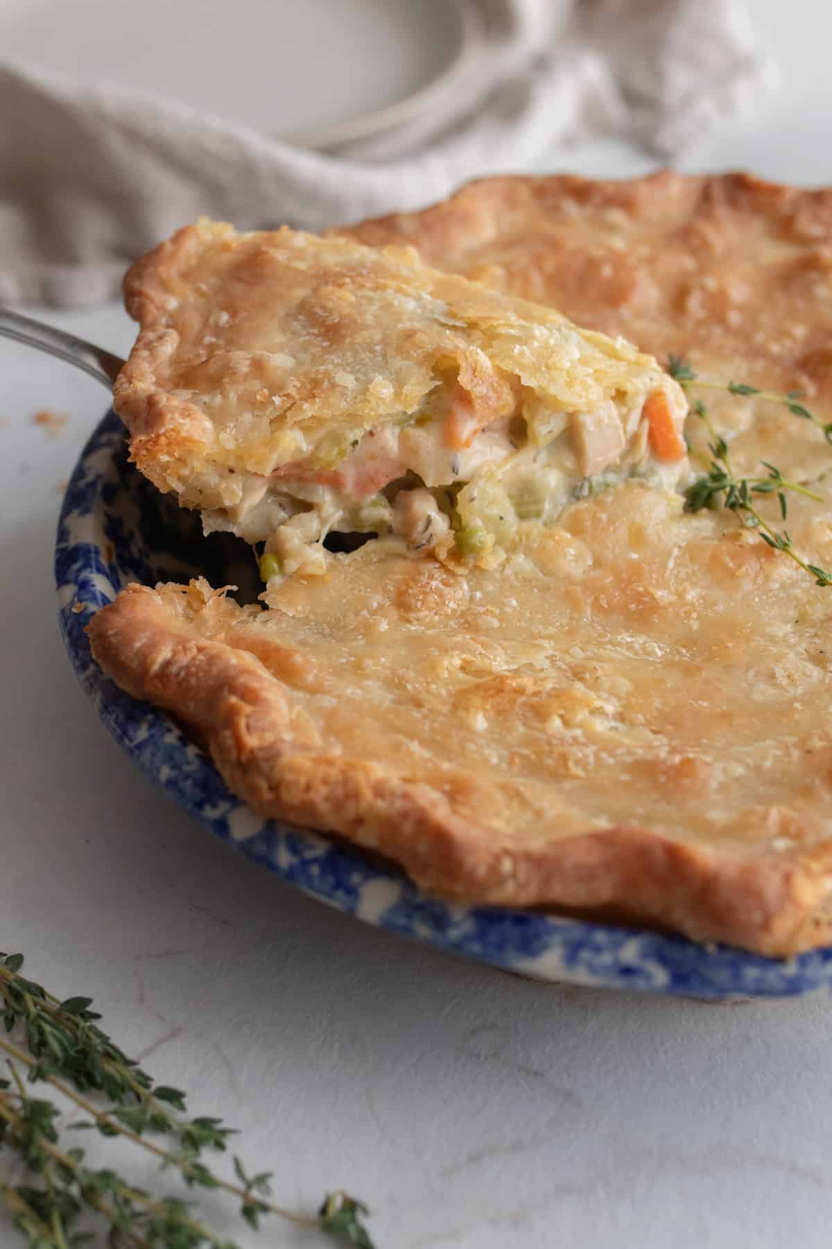 A slice of chicken pot pie being lifted out of a pie plate.