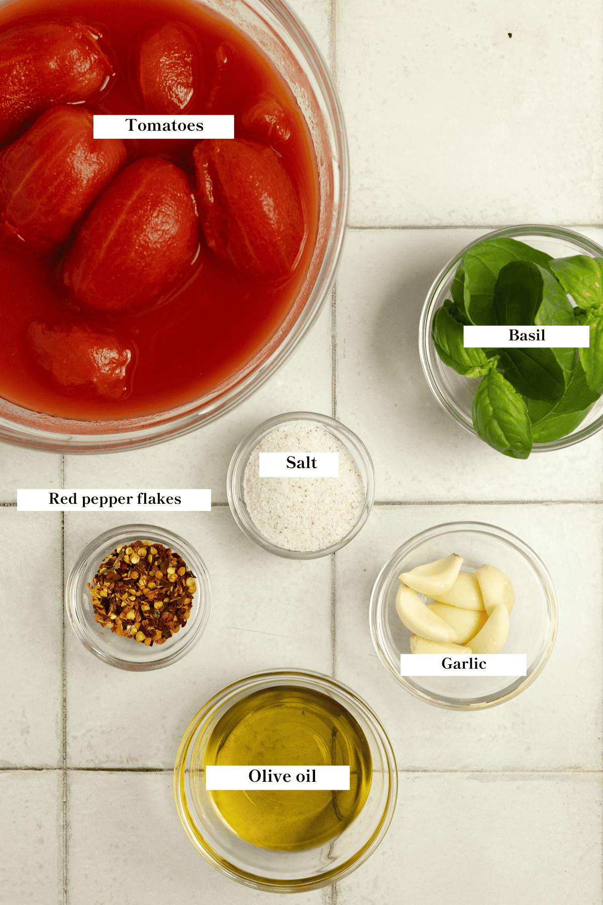 Tomatoes, basil, garlic, and olive oil sitting on the counter.