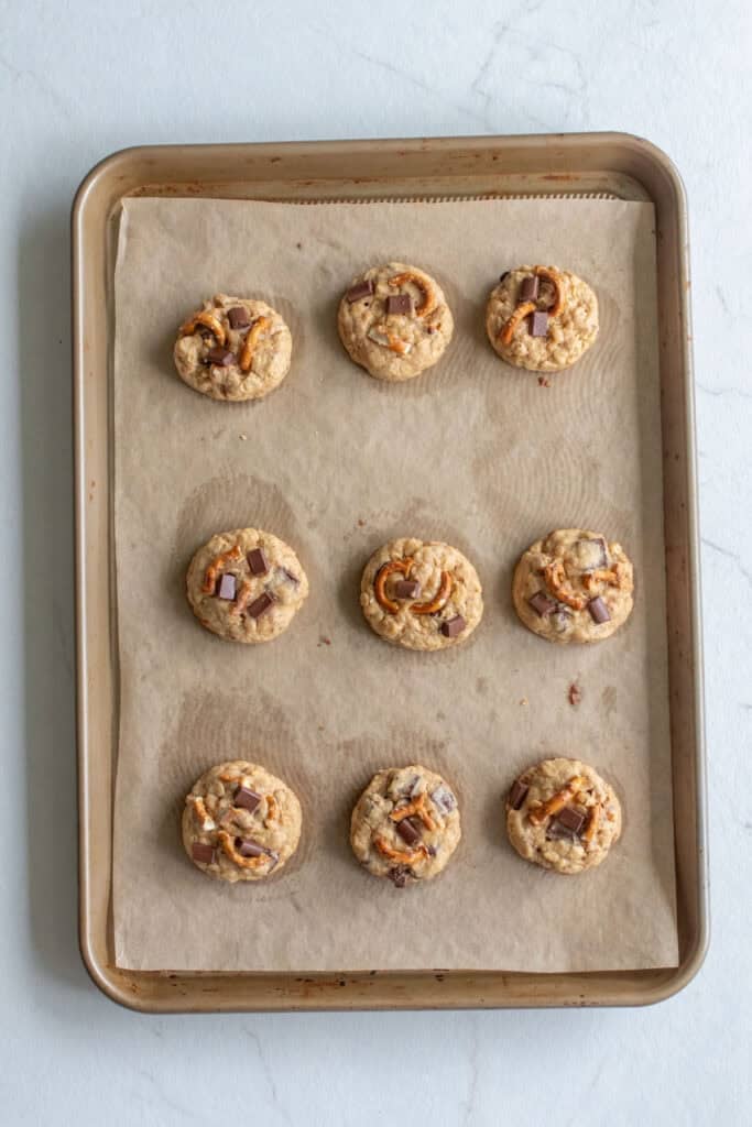 Cookie dough balls on a parchment lined baking sheet.