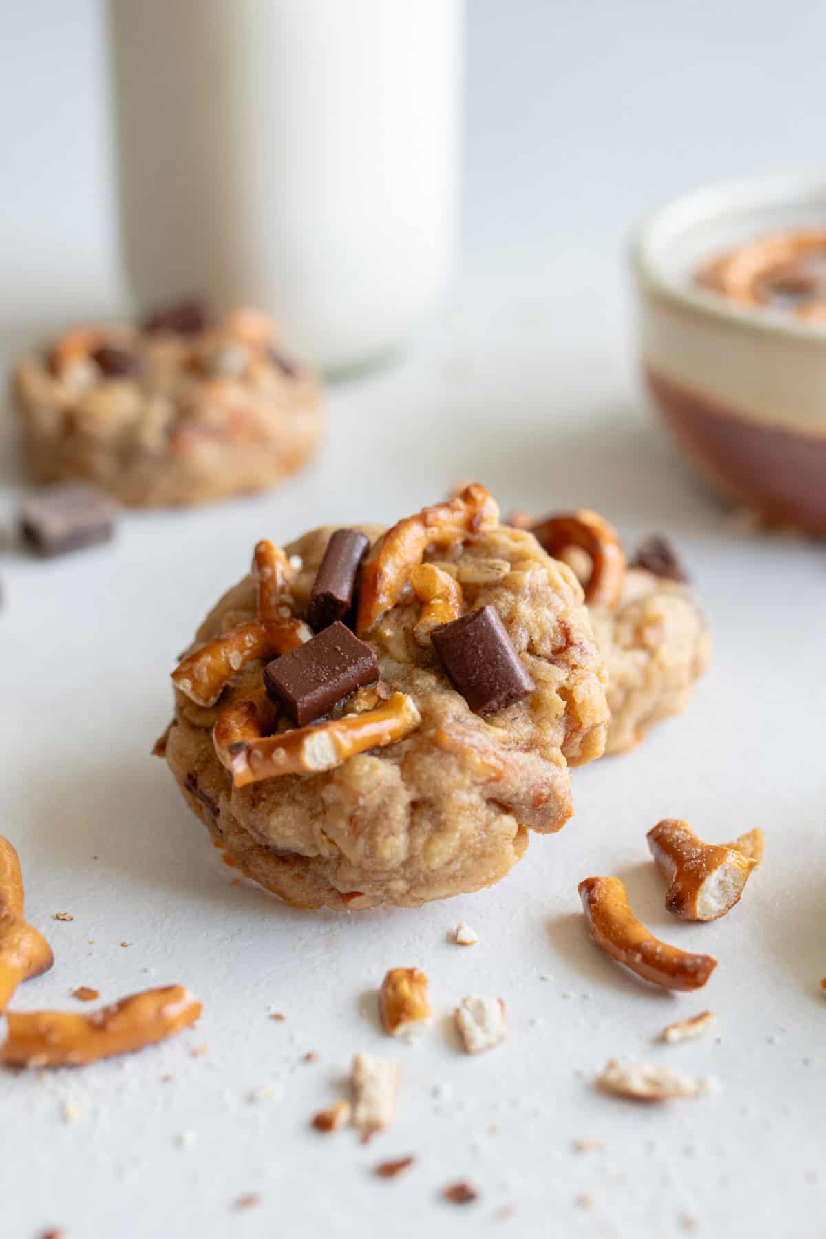 Lactation cookies made with oats, pretzels and chocolate chips on a white countertop.