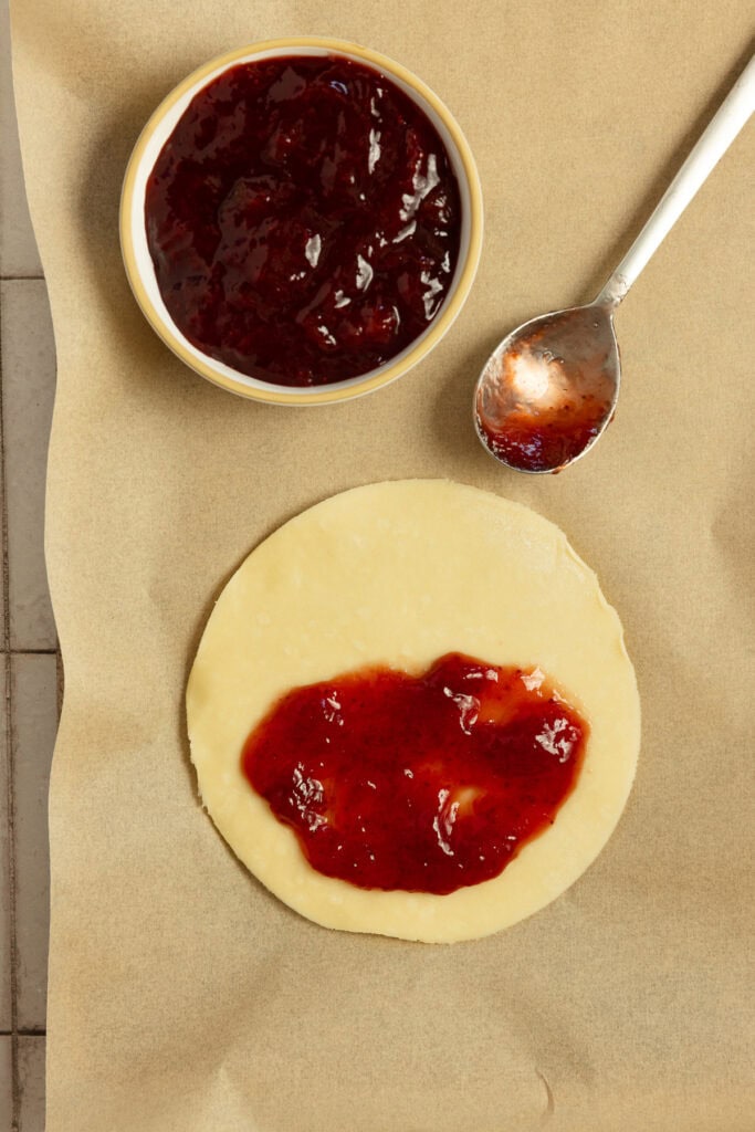 Adding strawberry jam pie dough cut into a circle.
