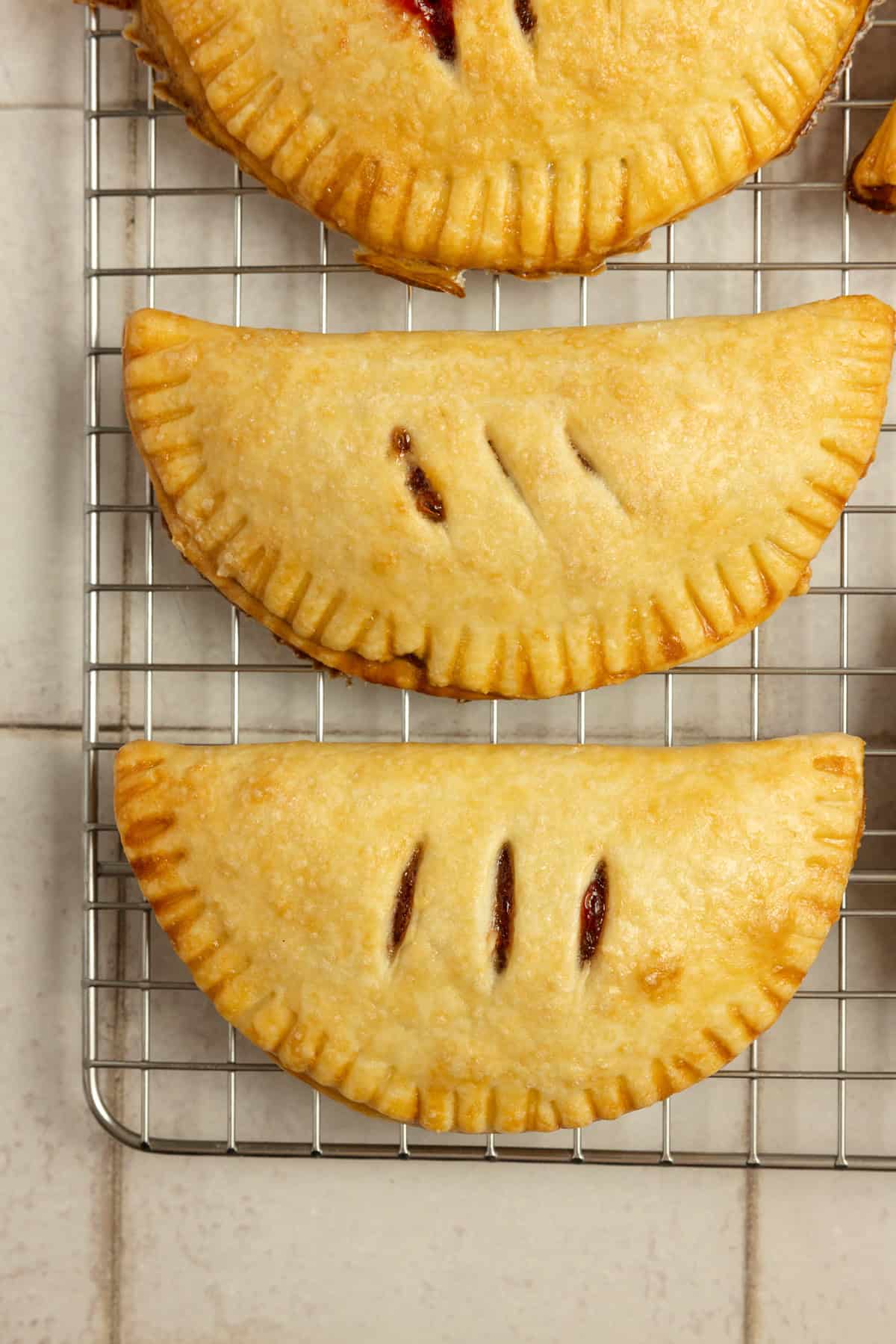 3 strawberry hand pies on a cooling rack.
