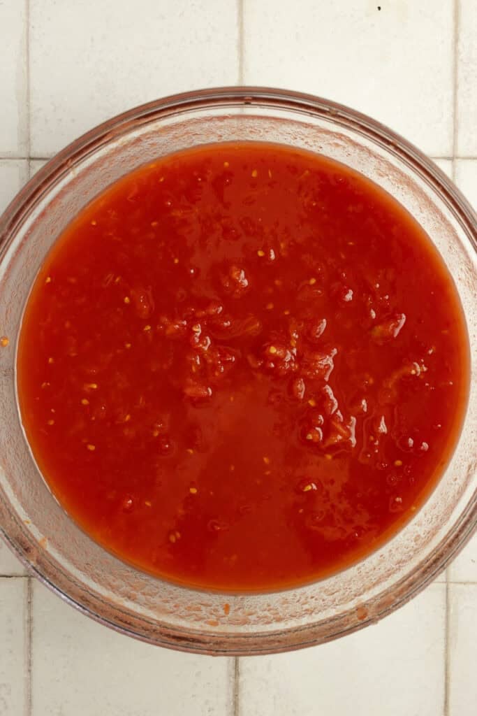 Crushed tomatoes in a glass bowl on the counter.
