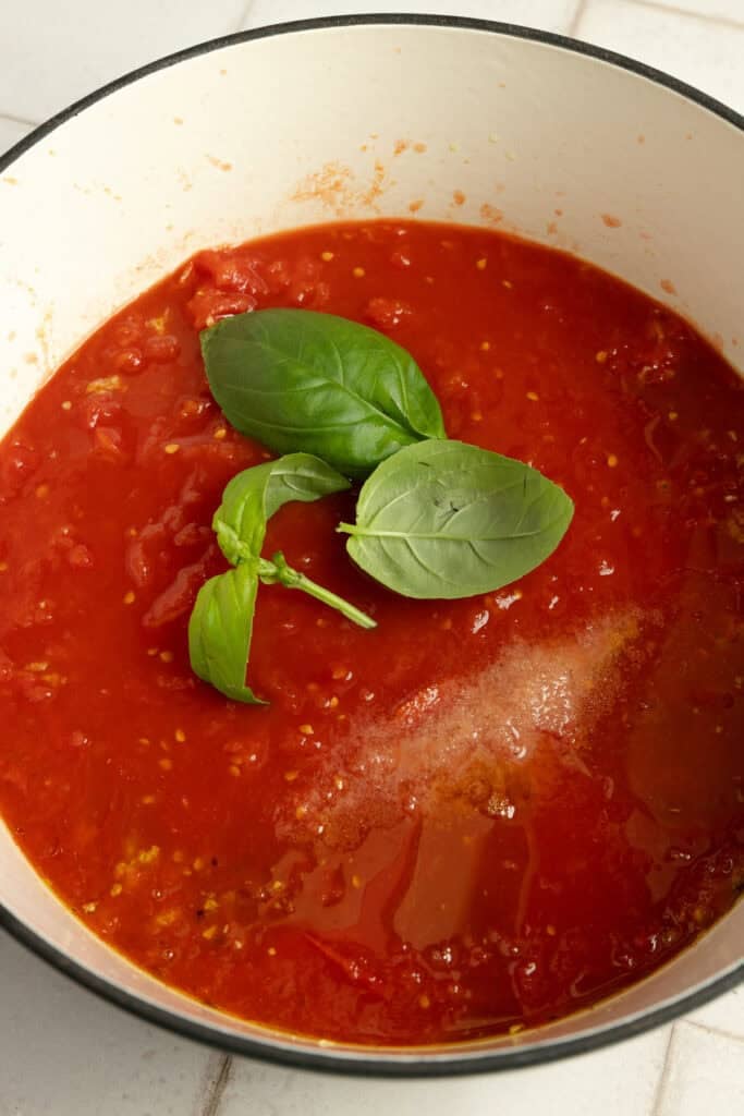 Tomato sauce cooking in a skillet with basil.