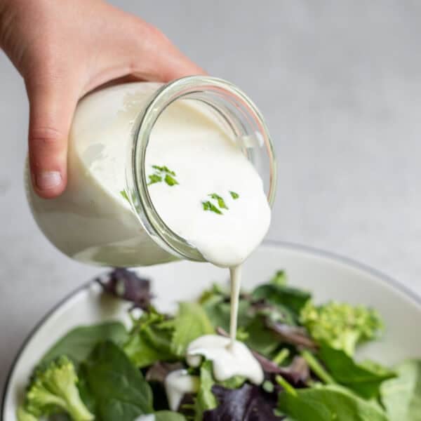 Pouring ranch dressing over a salad.