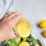 Pouring honey mustard dressing onto a salad.