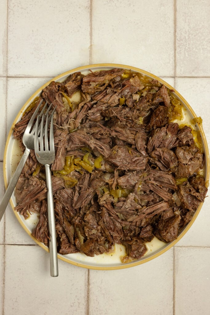 Shredded beef on a plate with two forks.