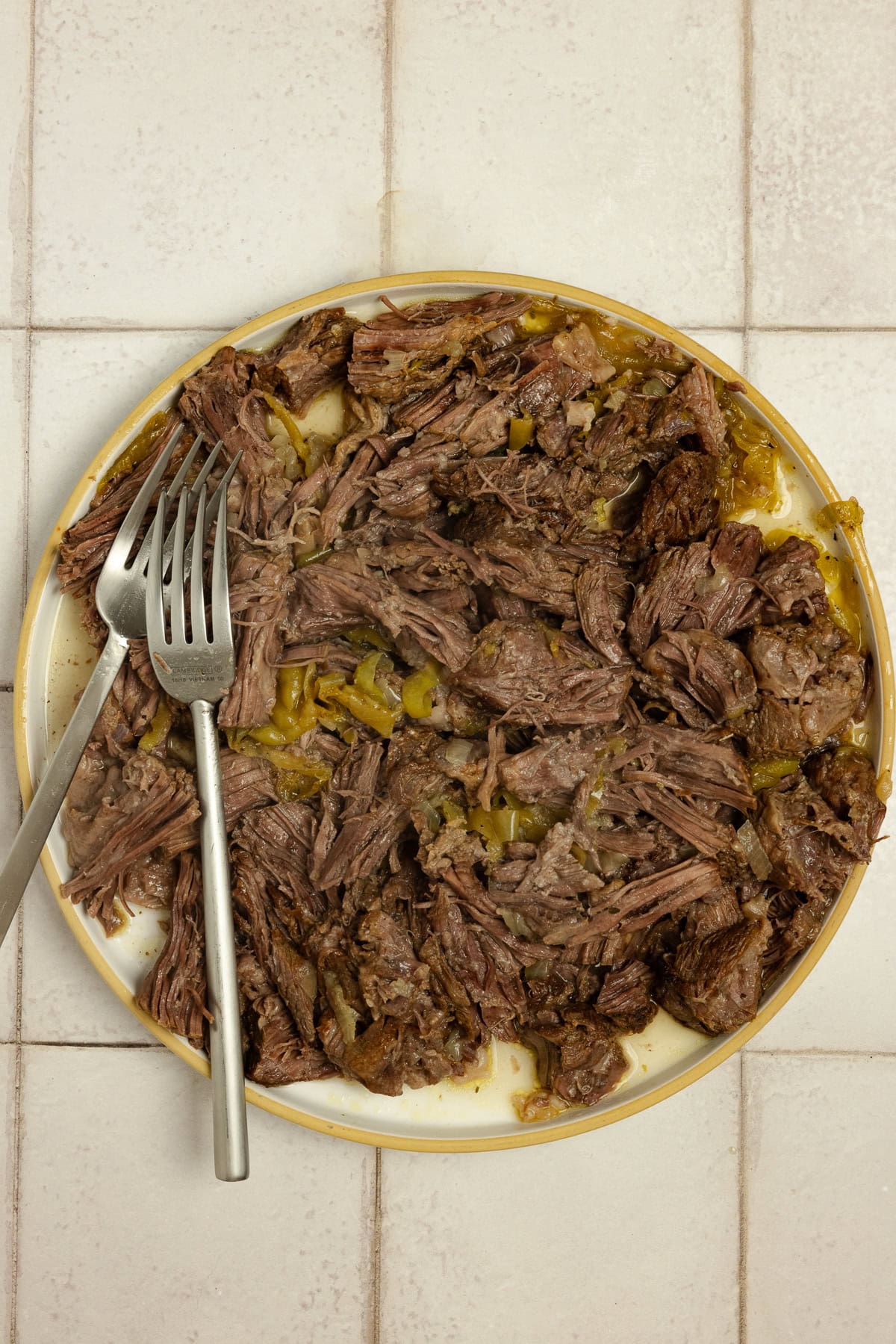 Shredded beef on a plate with two forks.