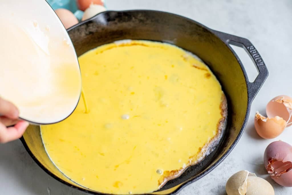 Pouring eggs into a hot skillet.