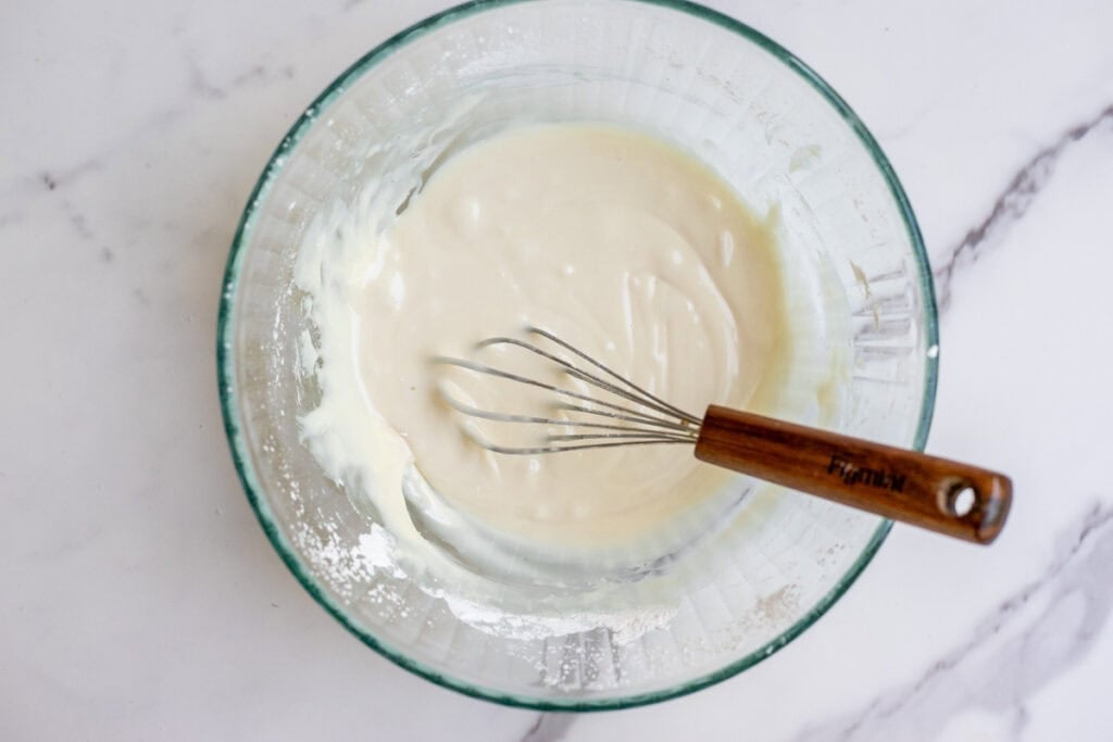 Glaze mixed together in a white bowl with a whisk.