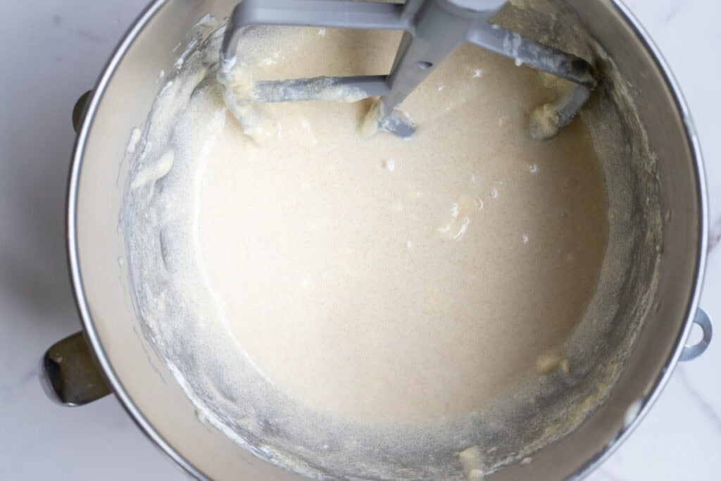 Butter, sugar, sour cream, and sourdough starter whipped together in a stand mixer bowl.