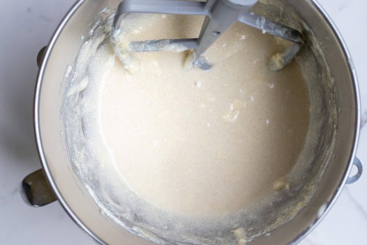 Butter, sugar, sour cream, and sourdough starter whipped together in a stand mixer bowl.